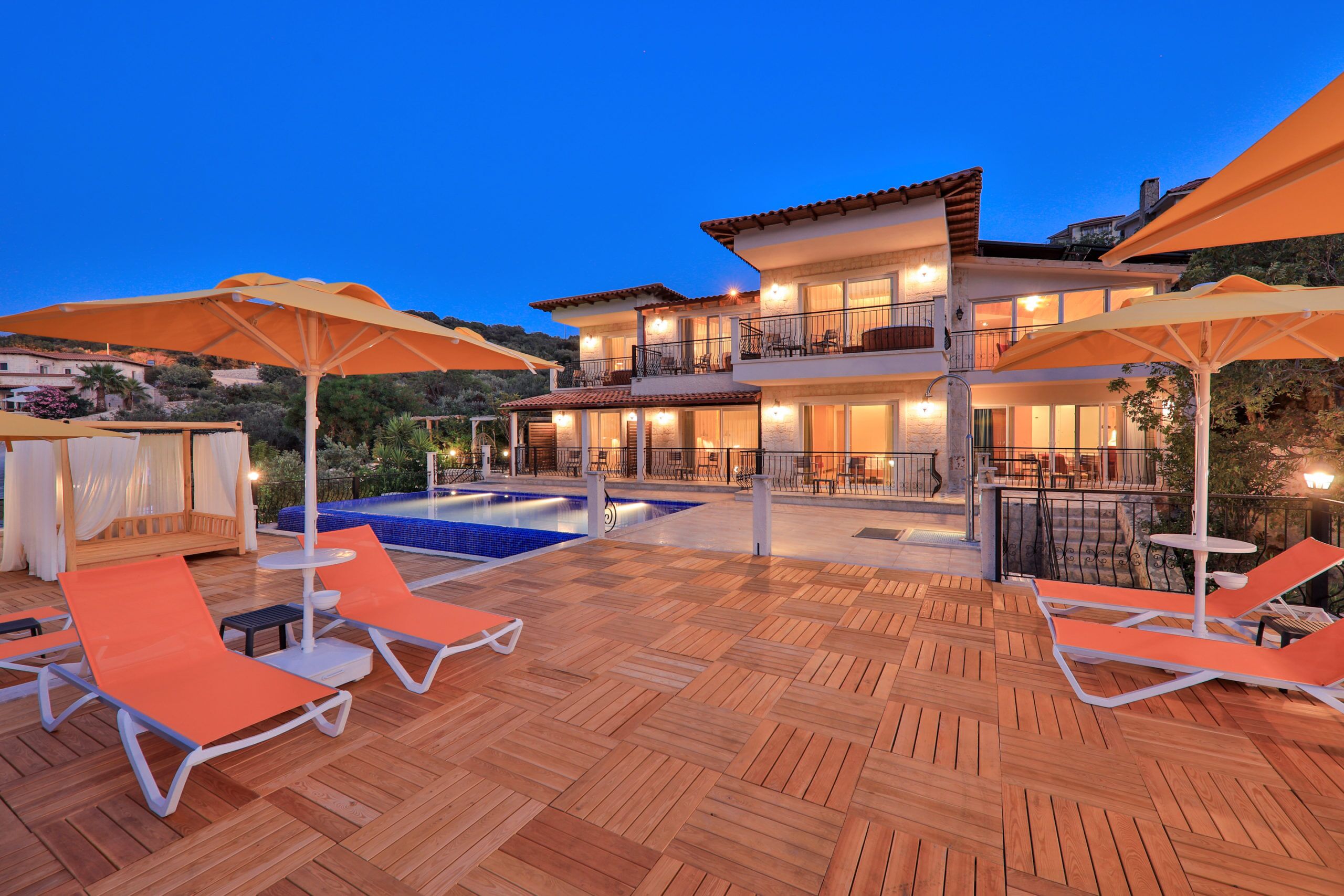 A two-story building with a swimming pool, outdoor seating, and umbrellas.