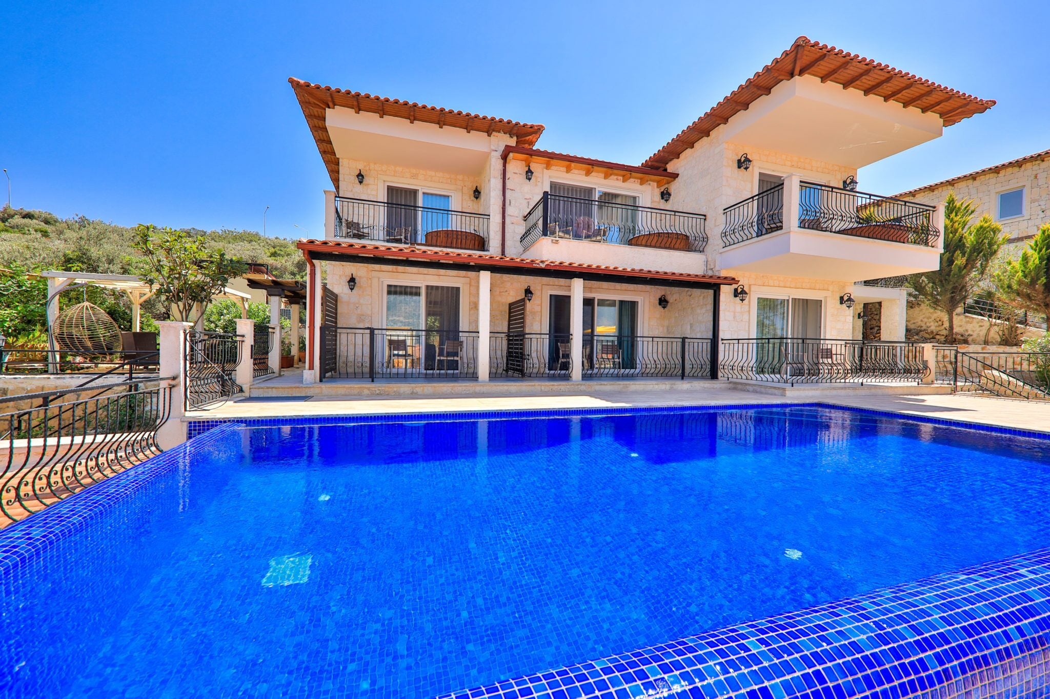 A two-story house with a swimming pool in front.