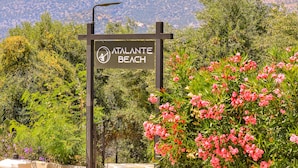 A sign for Atalante Beach with a clear view of the surrounding greenery and flowers.