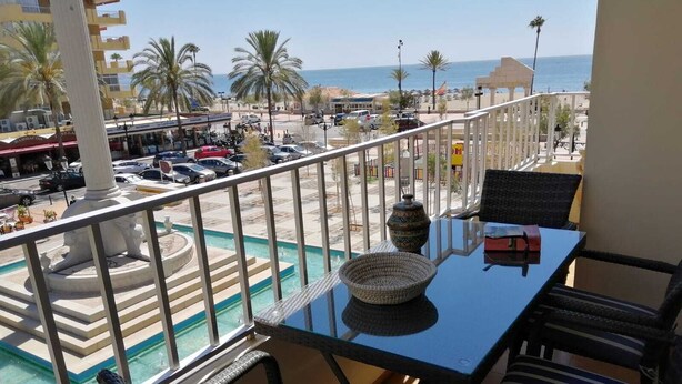 Un balcon avec vue sur une piscine, des palmiers et une plage.