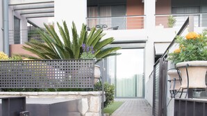 A narrow staircase leading to a modern building with a metal fence on one side and a planter on the other.