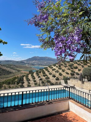A poolside view with a clear view of the surrounding landscape, including terraced fields and distant mountains. - Cortijo Rocas Altas (Iznájar)