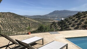 A poolside area with two lounge chairs and a view of a mountainous landscape.