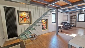 Un interno moderno con una scala, parquet, un divano e una zona pranzo.