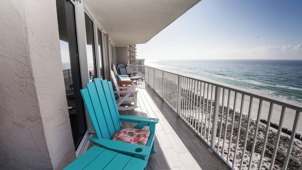 A balcony with turquoise chairs and a table, overlooking a beach with a railing. - E1101 Gulf Front, Amazing View, 3 Pools, Gated Condo (Panama City)