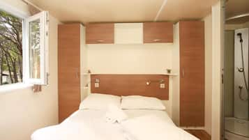 A bedroom with a bed, a window, a shower, and built-in wooden cabinets.