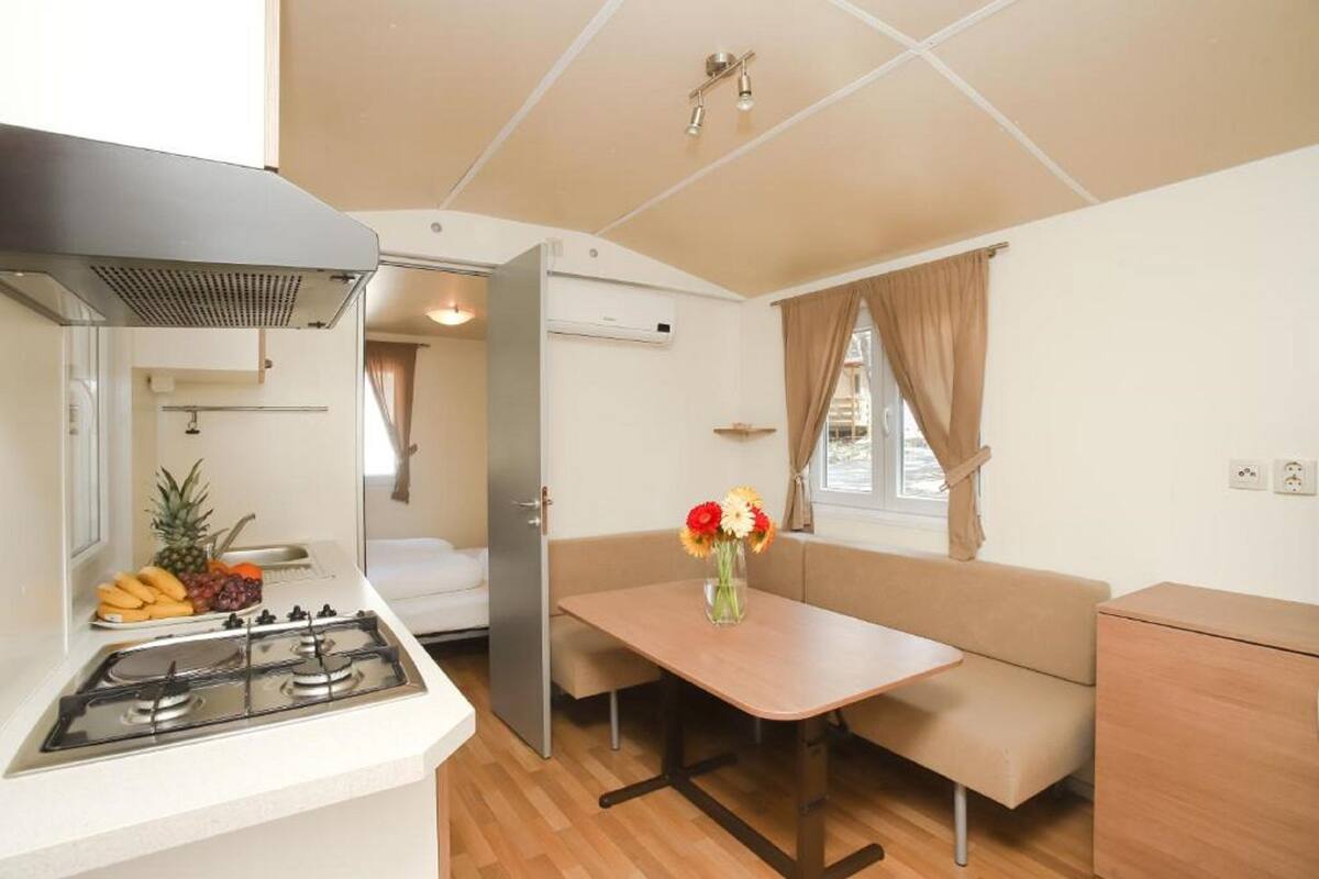 A compact kitchen with a gas stove, a sink, and a dining area with a table and bench.