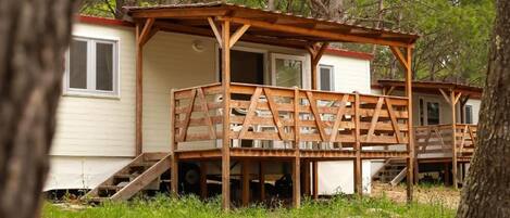 A wooden deck structure attached to a cabin with a ramp leading to the entrance.