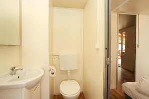 A small bathroom with a sink, toilet, and a door leading to another room. - Mediteran Travel Mobile Homes Basko Polje (Baska Voda)