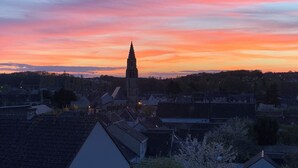 Un pueblo con una imponente torre de iglesia silueteada contra un cielo de atardecer colorido.