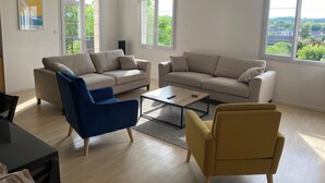 Un salón amplio con dos sofás, una mesa de centro y un sillón azul.