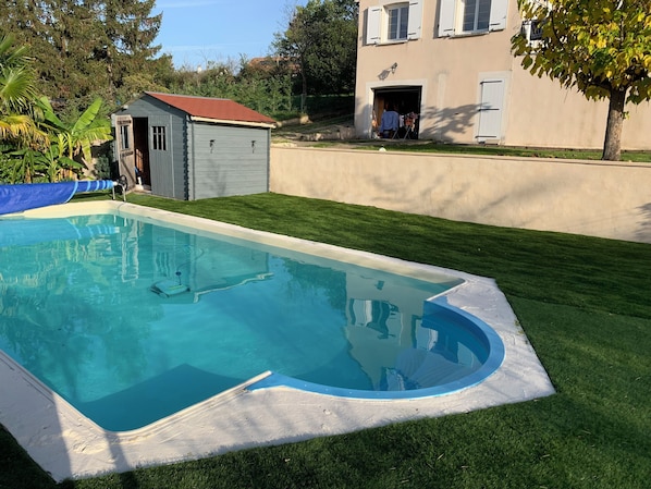 A swimming pool with a surrounding grassy area and a small shed.