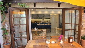 A wooden dining table set with placemats, cutlery, and a vase of flowers. - Gokova Hotel (Ula)