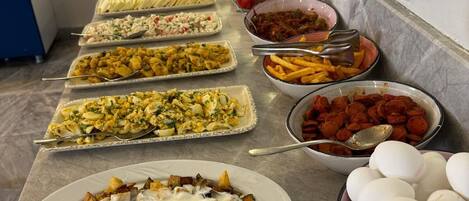 Una barra de buffet con diversos platos y un tazón de huevos.