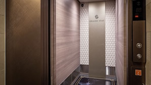 Interior de un ascensor con detalles metálicos, el logotipo