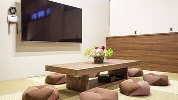 A modern dining area with a wooden table, a flat-screen TV mounted on the wall, and a vase with flowers.