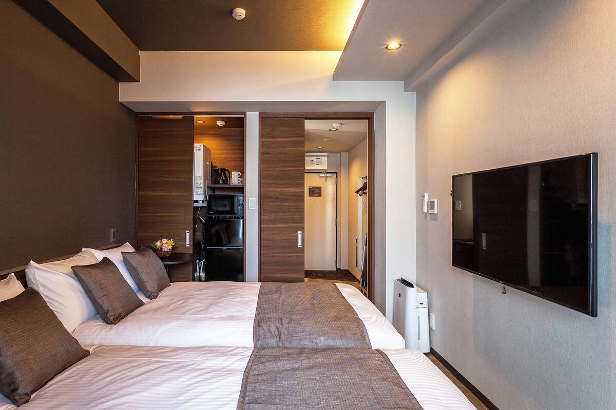 Une chambre d’hôtel moderne dotée d’un grand lit, d’un téléviseur à écran plat et d’une kitchenette.
