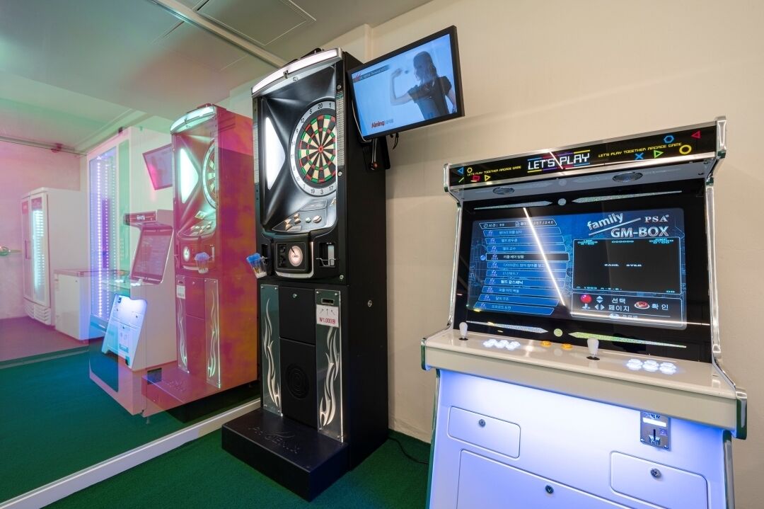 A gaming arcade with various machines, including a dartboard and a Family PS4 console.