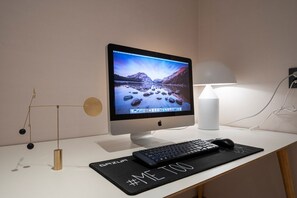 A desktop computer with a monitor displaying a scenic wallpaper, a keyboard, a mouse, a desk lamp, and a decorative hanging object. - Knockin Hotel Daejeon by Anook (Daejeon)