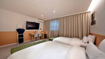 Habitación de hotel con dos camas, un escritorio con silla, televisor y ventana con cortinas.