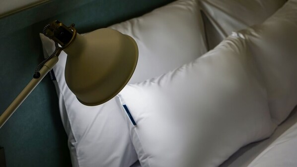 A bed with white pillows and a lamp on the side.