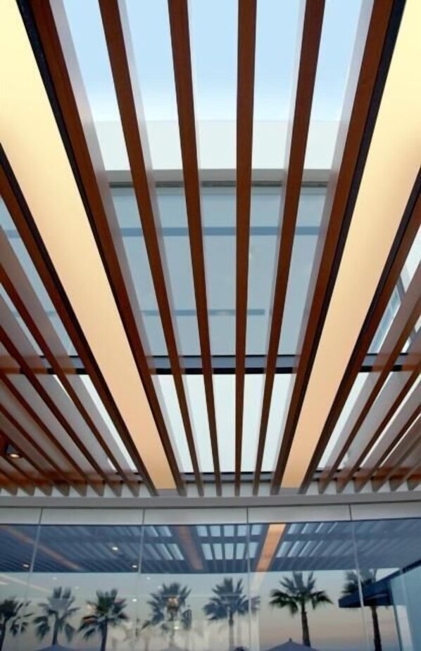 A modern interior with a slatted ceiling and glass walls reflecting palm trees. - Tesoro Blu Hotel & Spa - Adults Only (Kefalonia)