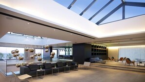 A spacious modern lobby with a high ceiling, a seating area with sofas and chairs, and a large window providing a view of the outdoors. - Tesoro Blu Hotel & Spa - Adults Only (Kefalonia)