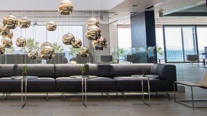 A modern lounge area with a black sofa, two white chairs, and a unique spherical chandelier. - Tesoro Blu Hotel & Spa - Adults Only (Kefalonia)