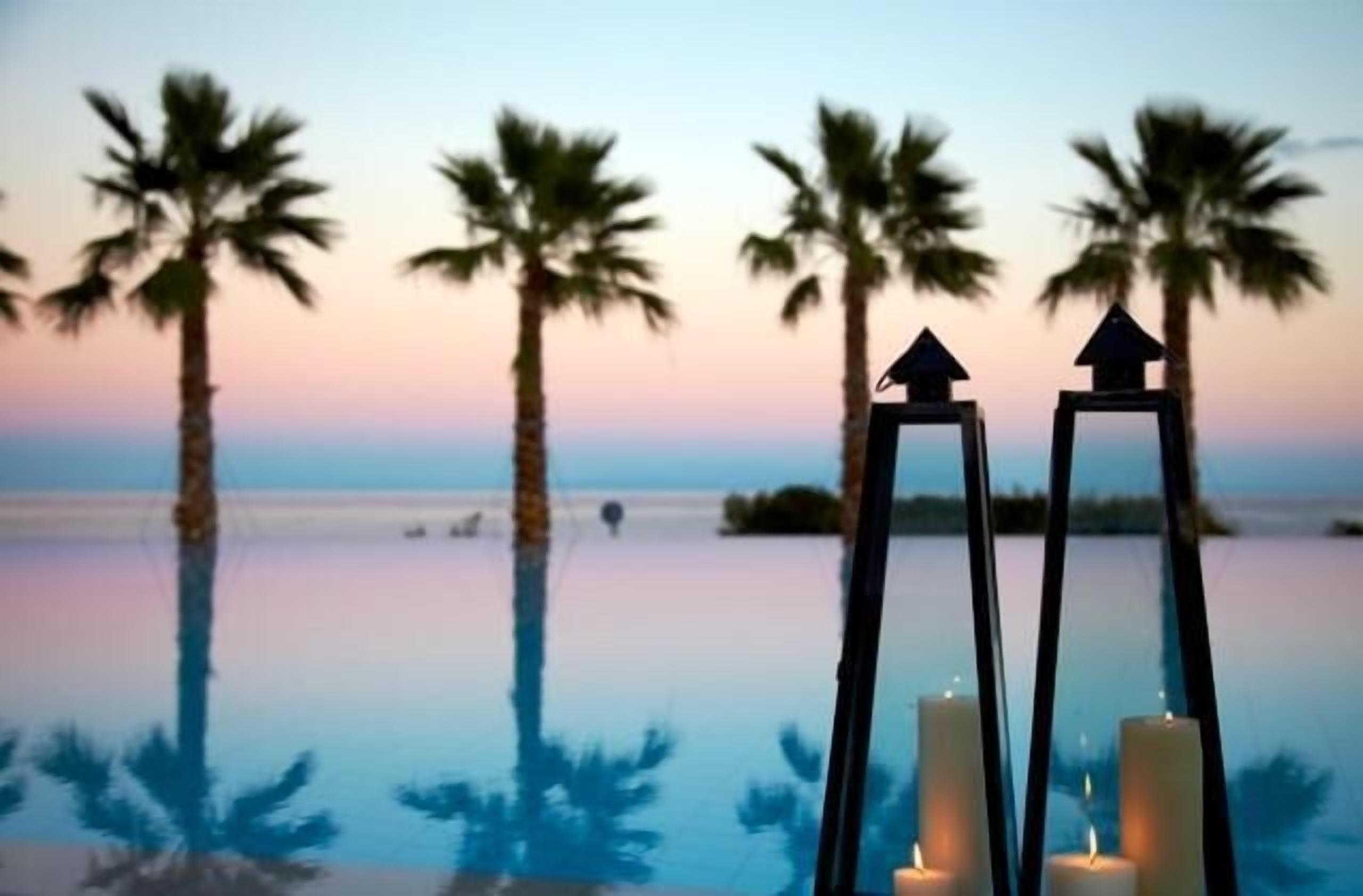 A serene poolside view with palm trees and candles.
