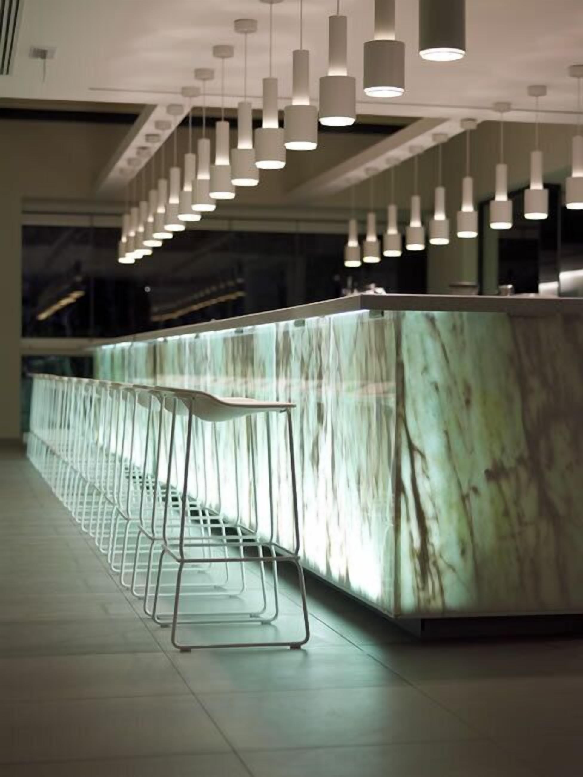 Un área de bar moderna con encimera de mármol y taburetes de metal.