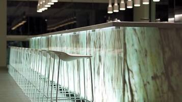 Un área de bar moderna con encimera de mármol y taburetes de metal.