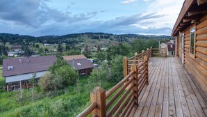 A wooden deck with a view of a rural landscape, including houses and trees. - Nederland Getaway 4 Bedroom Home by RedAwning (Nederland)