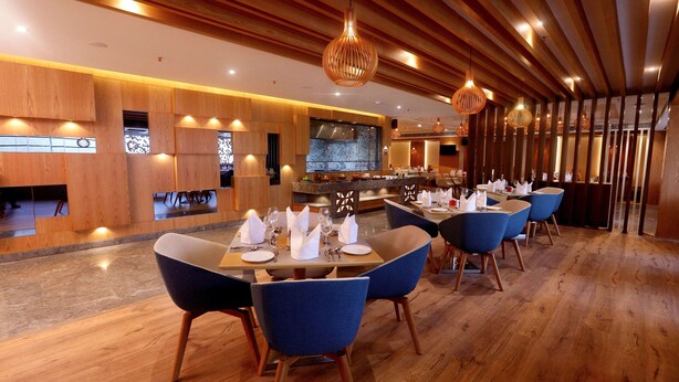 Un restaurante moderno con paneles de madera, sillas azules y una zona de bar central.