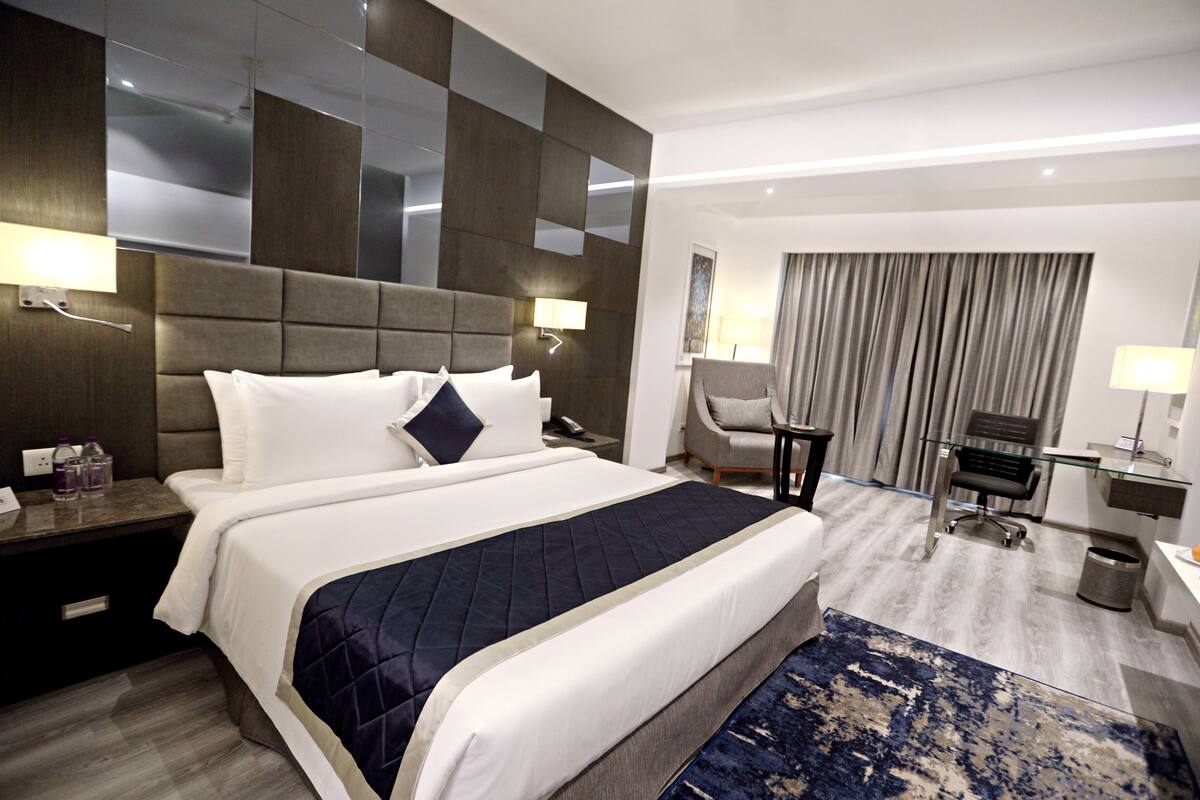 Une chambre d’hôtel moderne équipée d’un grand lit, d’un bureau, d’une chaise et d’une salle de bain.