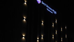 Exterior de un hotel de noche con señalización iluminada que dice "Best Western PLUS Tejuiyaan".