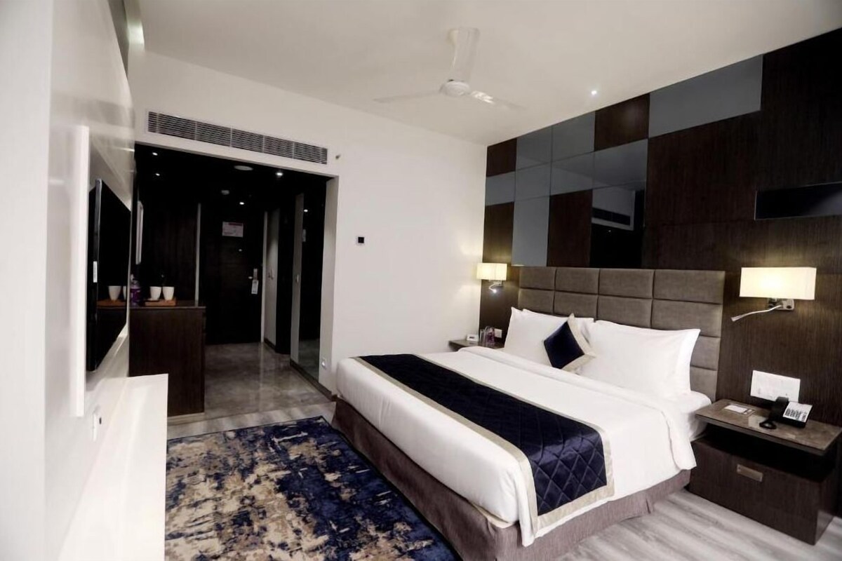 Une chambre d’hôtel moderne dotée d’un grand lit, de tables de chevet, d’un téléviseur à écran plat et d’un ventilateur de plafond.