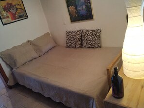 A bedroom with a bed, two leopard print pillows, a bottle on a nightstand, and a painting on the wall. - Beautiful Beach House At Sounio (Lavreotiki)