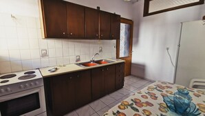 A kitchen with a stove, sink, and wooden cabinets.