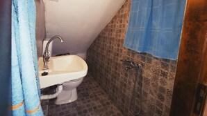 A small bathroom with a toilet, sink, and shower.