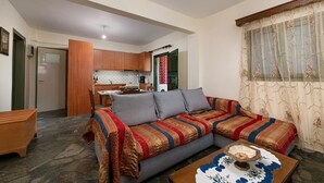 Ein Wohnzimmer mit Sofa, Couchtisch und einer Küche im Hintergrund.