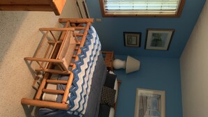 Una habitación con una cama, una ventana con persianas, una lámpara y cuadros en la pared.