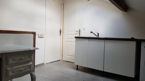 A small, compact kitchen with white cabinets, a sink, and a countertop.