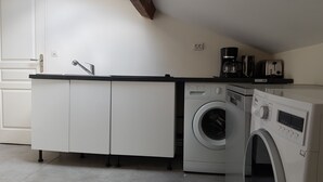 A compact kitchen with a built-in washing machine and a coffee maker.