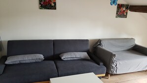 A living room with a dark grey sofa, a grey armchair, and a white coffee table.