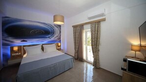 Une chambre d’hôtel moderne dotée d’un grand lit, d’un téléviseur à écran plat, d’un luminaire au plafond et d’une fenêtre avec des rideaux.
