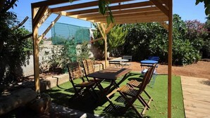 An outdoor patio with a wooden pergola, a table, and chairs. - XDream Suite I (Hersonissos)