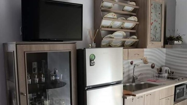 Une cuisine équipée d’un réfrigérateur, d’un four à micro-ondes, d’un évier et d’un téléviseur posé sur le dessus du réfrigérateur.