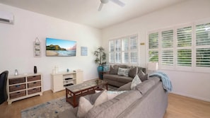 A living room with a sofa, coffee table, and a television displaying a scenic landscape.