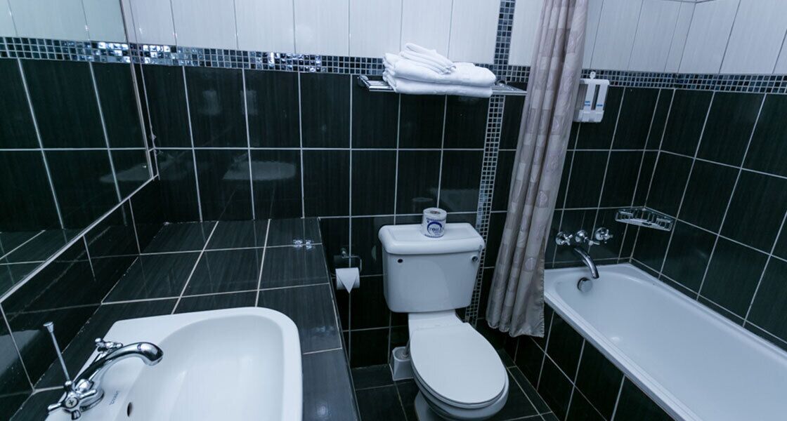 A bathroom with a white sink, toilet, and bathtub, all with chrome fixtures.