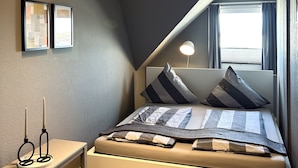 Un dormitorio moderno con cama, mesita de noche y ventana con cortinas.